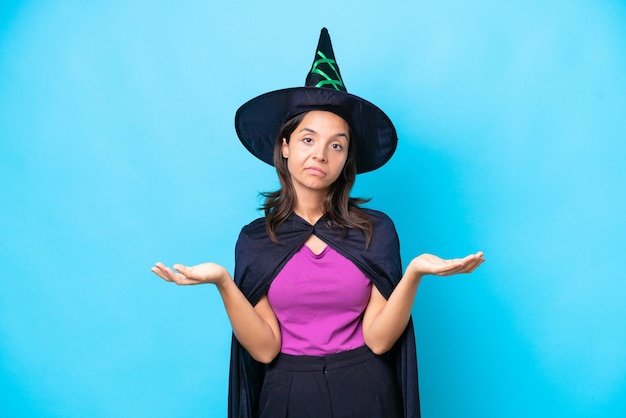 Young hispanic woman dressed as witch over isolated background having doubts