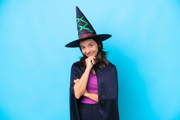 Young hispanic woman dressed as witch over isolated background looking to the side and smiling