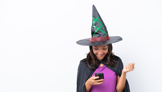 Young hispanic woman dressed as witch over isolated background surprised and sending a message