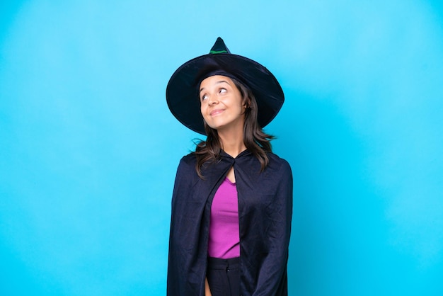 Young hispanic woman dressed as witch over isolated background thinking an idea while looking up