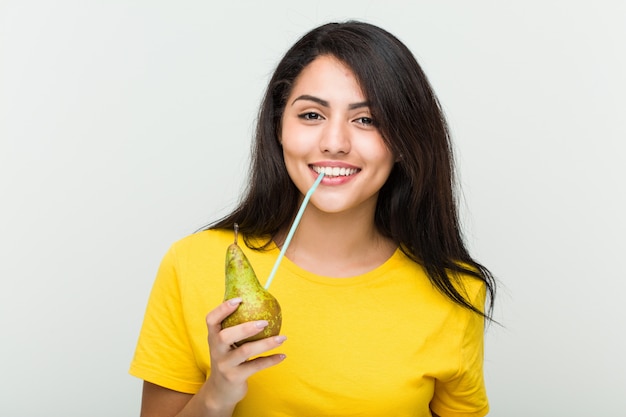 Young hispanic woman drinking a pear juice with a straw