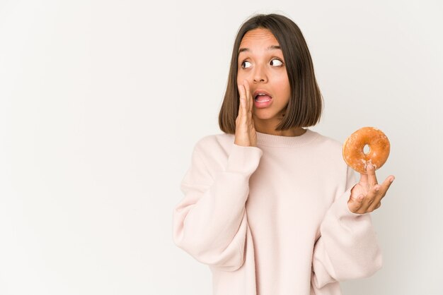 Young hispanic woman eating a doughnut