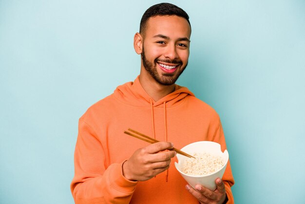 青い背景に分離された麺を食べる若いヒスパニック系女性