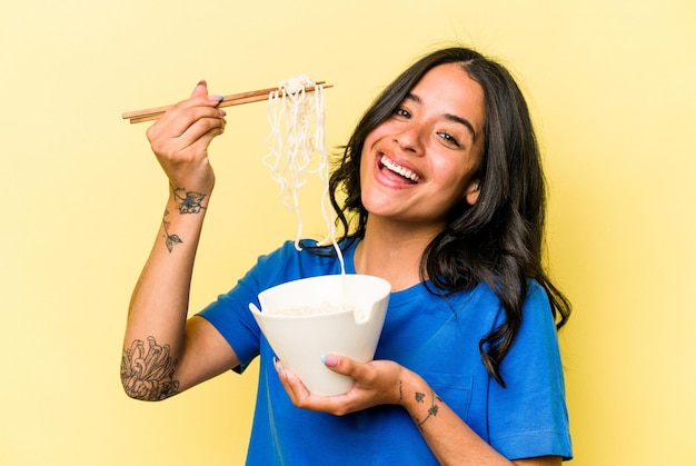 写真 黄色の背景に分離された麺を食べる若いヒスパニック系女性