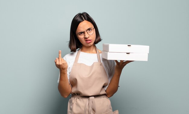 Young hispanic woman feeling angry, annoyed, rebellious and aggressive, flipping the middle finger, fighting back