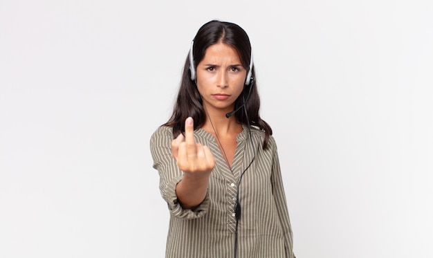 Foto giovane donna ispanica che si sente arrabbiata, infastidita, ribelle e aggressiva con un auricolare. concetto di telemarketing