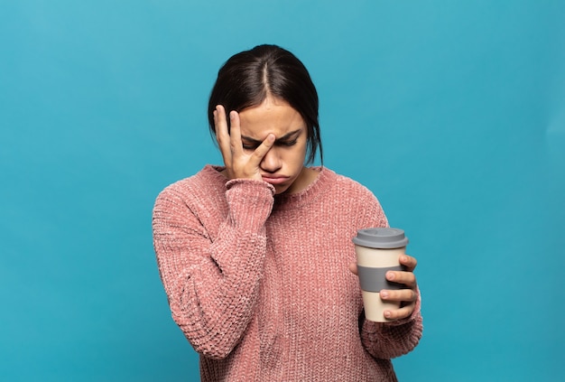 Young hispanic woman feeling bored, frustrated and sleepy after a tiresome, dull and tedious task, holding face with hand