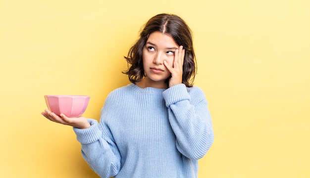 young hispanic woman feeling bored, frustrated and sleepy after a tiresome. empty bowl concept