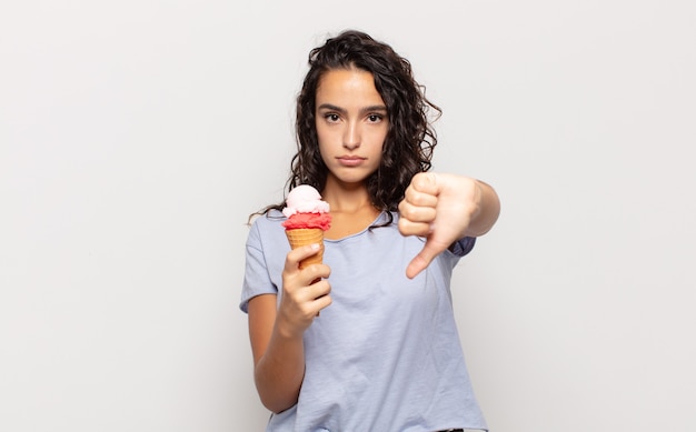 Young hispanic woman feeling cross, angry, annoyed, disappointed or displeased, showing thumbs down with a serious look