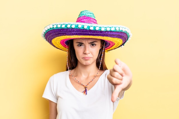 Young hispanic woman feeling cross,showing thumbs down. mexican hat concept