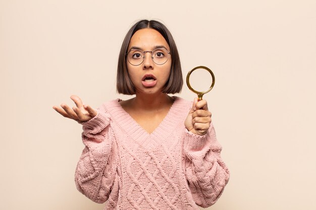 Young hispanic woman feeling extremely shocked and surprised, anxious and panicking, with a stressed and horrified look