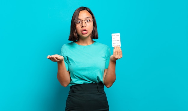 Young hispanic woman feeling extremely shocked and surprised, anxious and panicking, with a stressed and horrified look