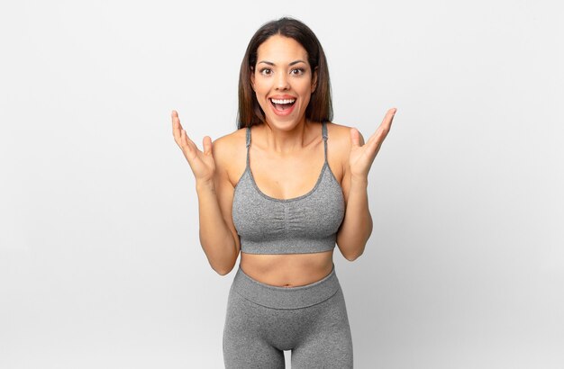 Young hispanic woman feeling happy and astonished at something unbelievable. fitness concept