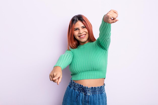 Young hispanic woman feeling happy and confident, pointing to camera with both hands and laughing, choosing you