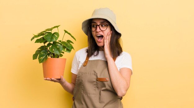 幸せな興奮と驚きの庭師と植物の概念を感じている若いヒスパニック系の女性