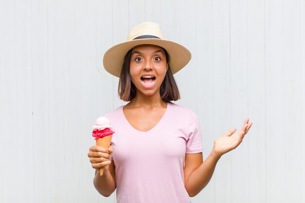 Young hispanic woman feeling happy, excited, surprised or shocked, smiling and astonished at something unbelievable