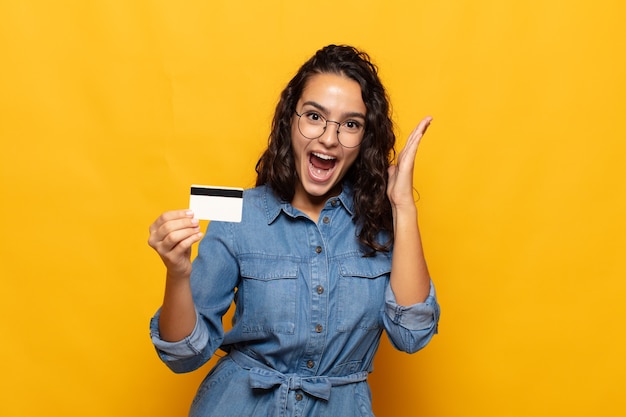 Young hispanic woman feeling happy, excited, surprised or shocked, smiling and astonished at something unbelievable