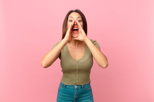 Young hispanic woman feeling happy,giving a big shout out with hands next to mouth