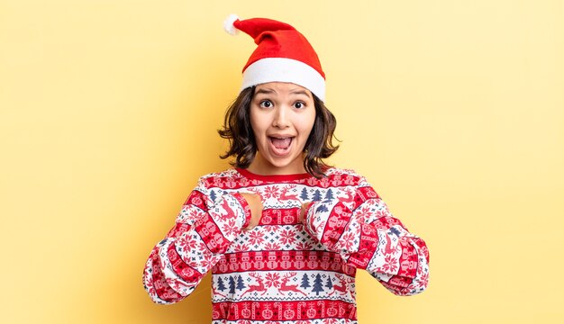 Young hispanic woman feeling happy and pointing to self with an excited. christmas concept