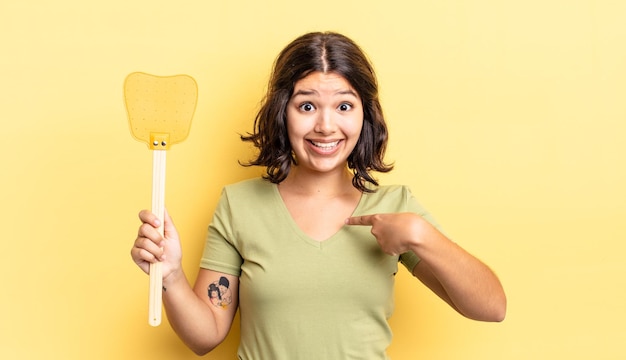 Young hispanic woman feeling happy and pointing to self with an excited. kill flies concept