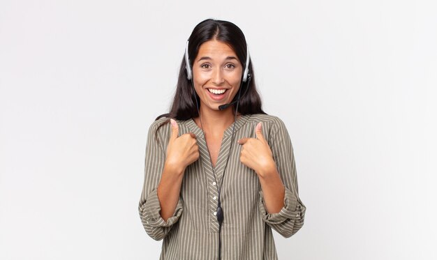 Young hispanic woman feeling happy and pointing to self with an excited with a headset. telemarketing concept