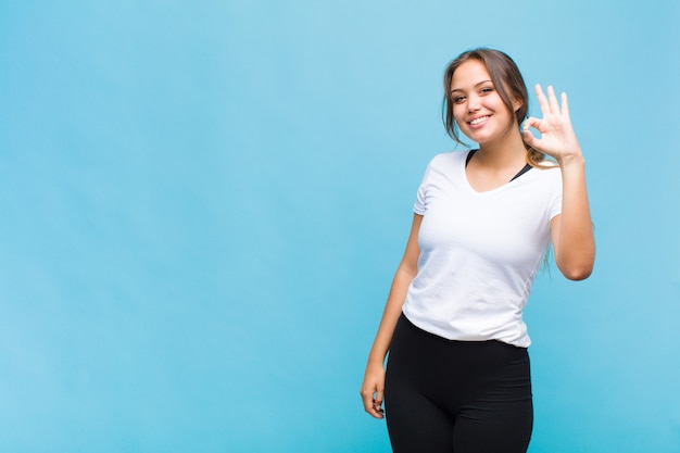 Young hispanic woman feeling happy, relaxed and satisfied, showing approval with okay gesture, smiling