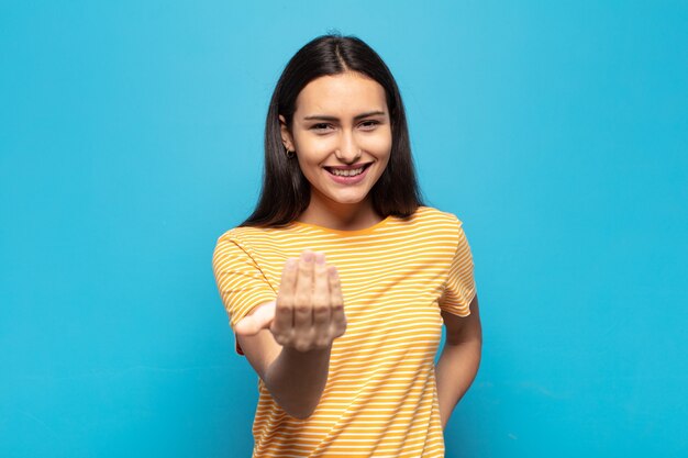 Young hispanic woman feeling happy, successful and confident, facing a challenge and saying bring it on! or welcoming you