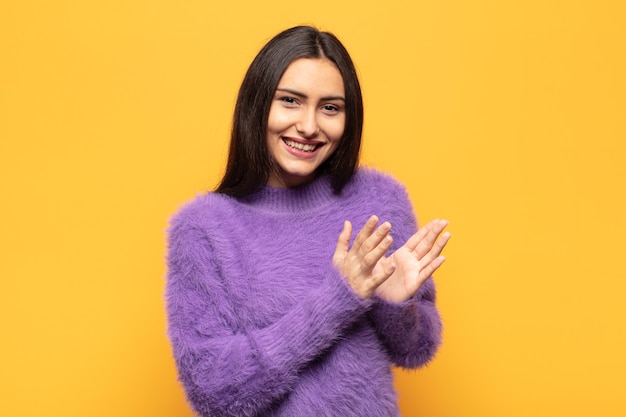 Young hispanic woman feeling happy and successful, smiling and clapping hands, saying congratulations with an applause