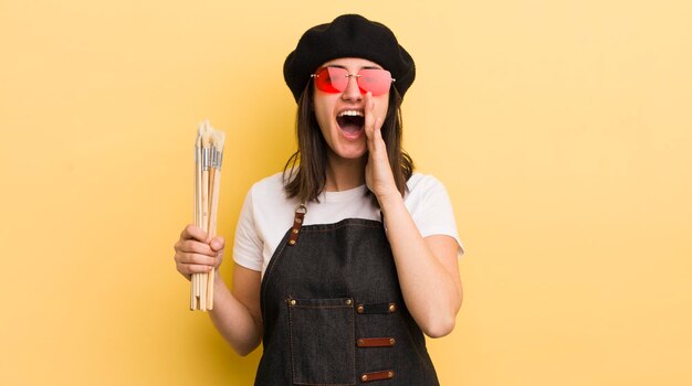 Young hispanic woman feeling happygiving a big shout out with hands next to mouth artist concept