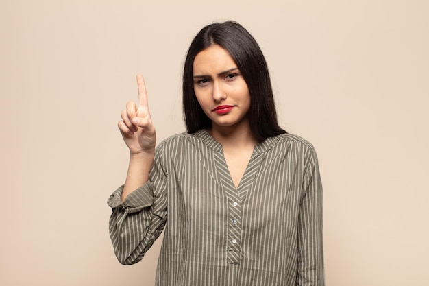 young hispanic woman feeling like a genius holding finger proudly up in the air after realizing a great idea, saying eureka