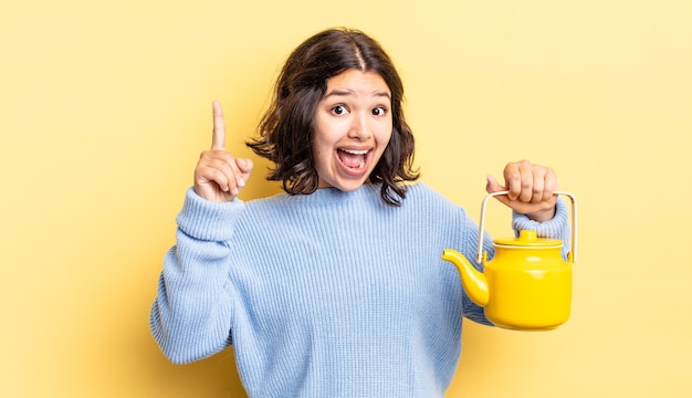 Young hispanic woman feeling like a happy and excited genius after realizing an idea. teapot concept