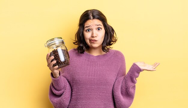 Young hispanic woman feeling puzzled and confused and doubting. coffee beans concept