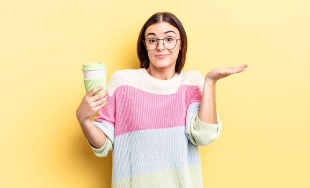 Young hispanic woman feeling puzzled and confused and doubting. take away coffee concept