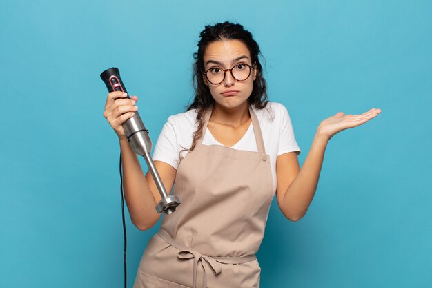 Young hispanic woman feeling puzzled and confused, doubting, weighting or choosing different options with funny expression