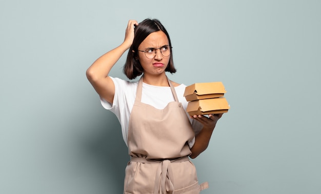 Young hispanic woman feeling puzzled and confused, scratching head and looking to the side