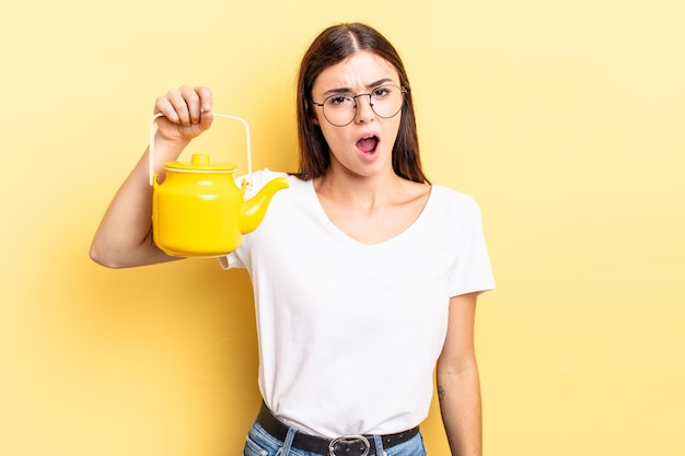 Young hispanic woman feeling puzzled and confused. teapot concept