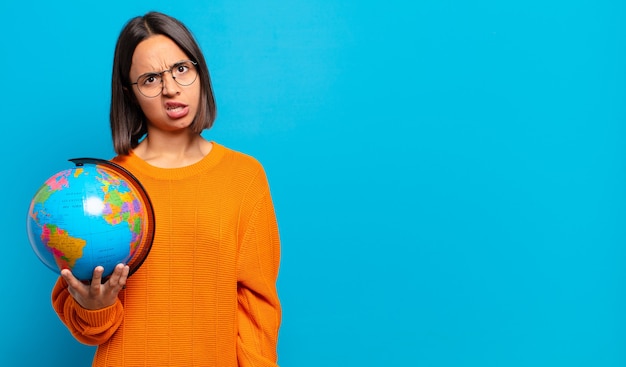 Young hispanic woman feeling puzzled and confused, with a dumb, stunned expression looking at something unexpected