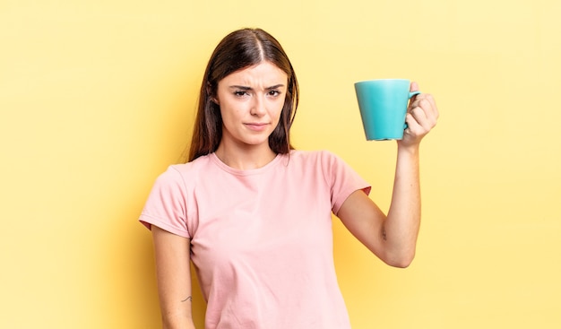 Young hispanic woman feeling sad, upset or angry and looking to the side. coffee cup concept