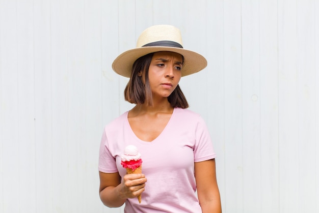 Young hispanic woman feeling sad, upset or angry and looking to the side with a negative attitude, frowning in disagreement