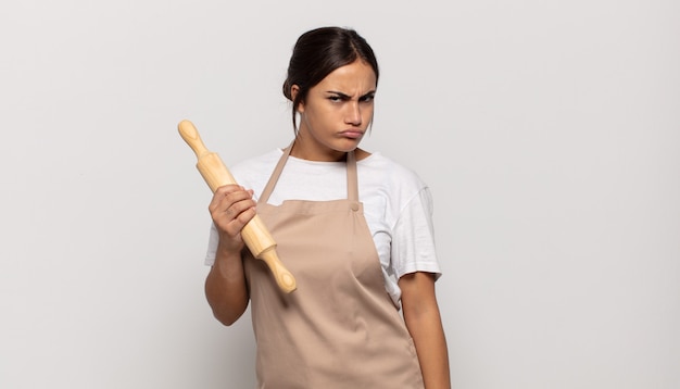 Young hispanic woman feeling sad, upset or angry and looking to the side with a negative attitude, frowning in disagreement