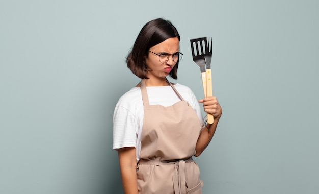 Young hispanic woman feeling sad, upset or angry and looking to the side with a negative attitude, frowning in disagreement