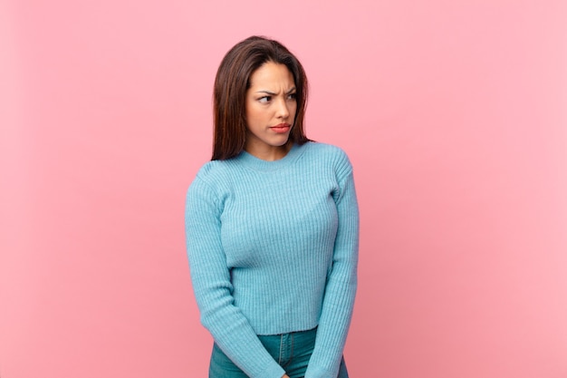 Young hispanic woman feeling sad, upset or angry and looking to the side