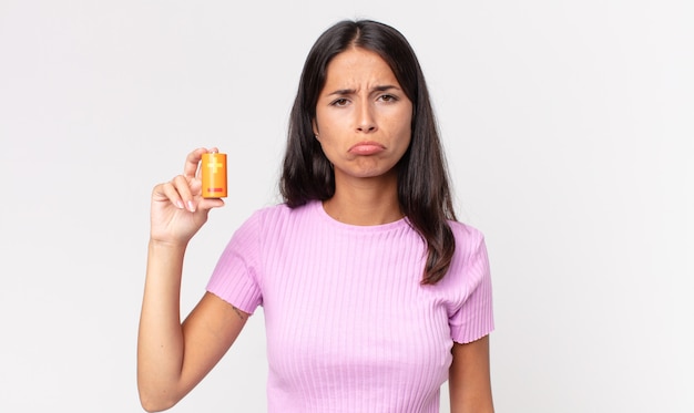 Young hispanic woman feeling sad and whiney with an unhappy look and crying and holding batteries