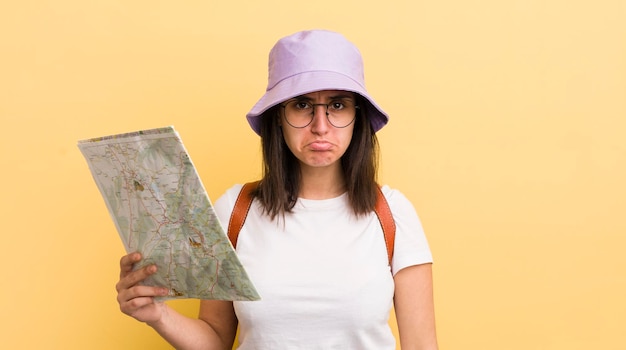 Young hispanic woman feeling sad and whiney with an unhappy look and crying tourist and map concept
