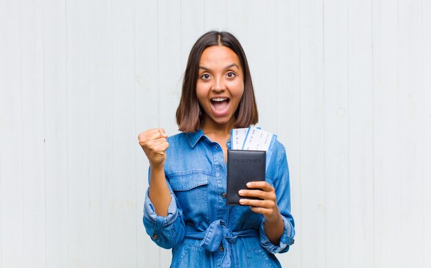 Young hispanic woman feeling shocked, excited and happy, laughing and celebrating success, saying wow!