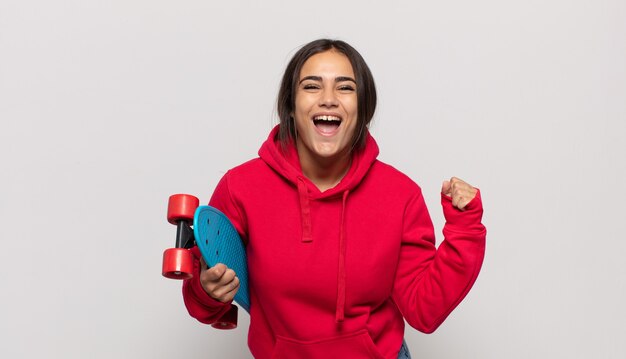 Young hispanic woman feeling shocked, excited and happy, laughing and celebrating success, saying wow!