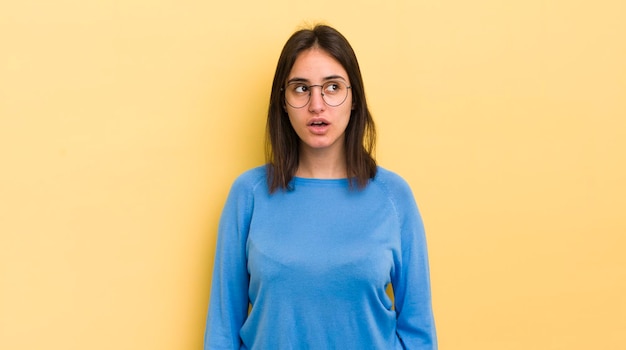 Photo young hispanic woman feeling shocked happy amazed and surprised looking to the side with open mouth