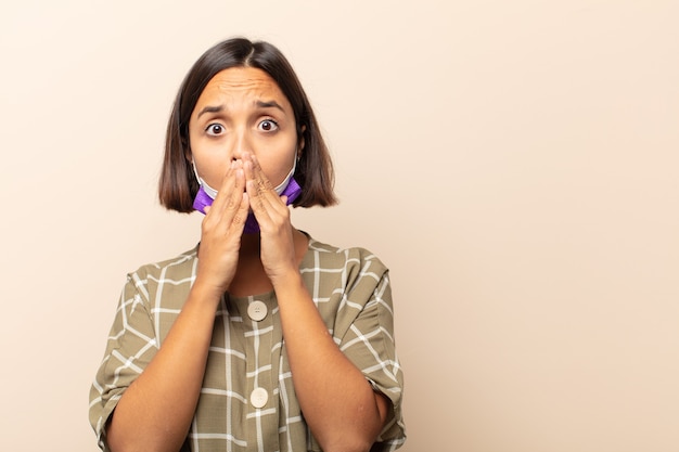 Young hispanic woman happy and excited, surprised and amazed covering mouth with hands, giggling with a cute expression