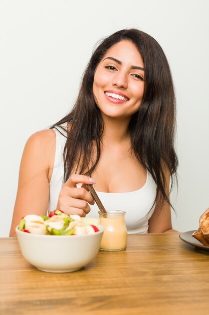 Young hispanic woman having breakfast on the table