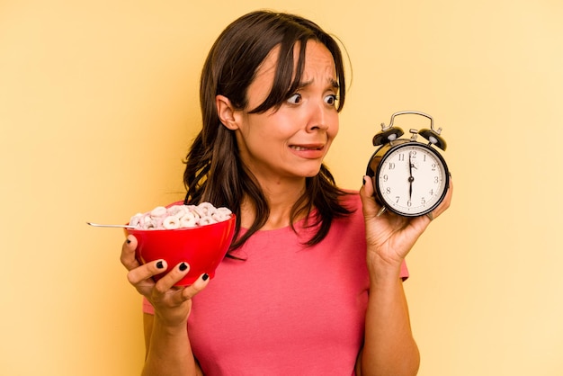 Photo young hispanic woman having a quick breakfast isolated on yellow background